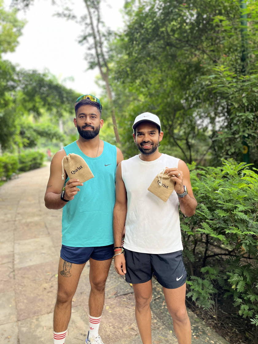 Two runners holding Qurist pouches on a tree-lined path