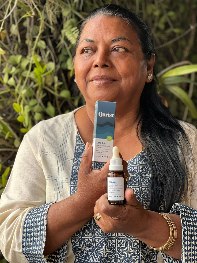 An older Qurist customer holding a bottle of CBD oil
